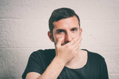 Adam gülüyor ve ağzını kapatıyor.