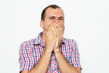 Adam gülüyor ve ağzını kapatıyor.