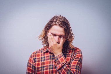  Adam elleriyle yüzünü kapatıyor.