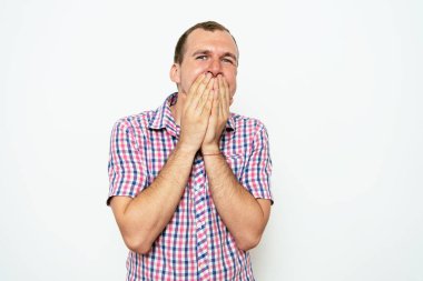 Adam gülüyor ve ağzını kapatıyor.