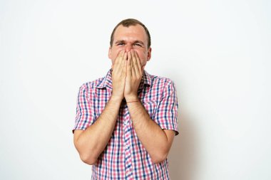 Adam gülüyor ve ağzını kapatıyor.