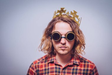 Kafasında plastik taç ve güneş gözlüğü olan bir adam.