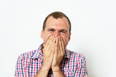 Adam gülüyor ve ağzını kapatıyor.