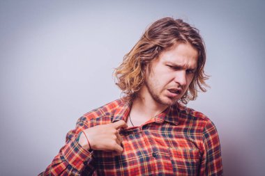 Delikanlının gömleği açarken çekilmiş portresi, çok sıcak. Negatif duygu, yüz ifadesi, his