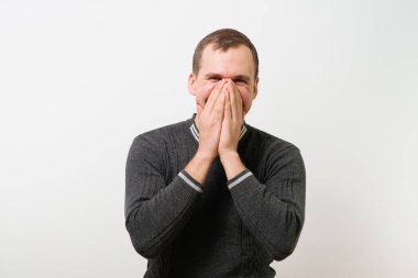 Adam gülüyor ve ağzını kapatıyor.