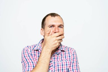 Adam gülüyor ve ağzını kapatıyor.