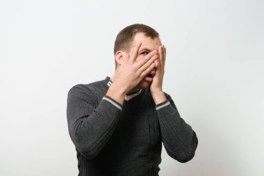  Adam elleriyle yüzünü kapatıyor.