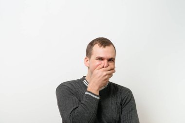 Adam gülüyor ve ağzını kapatıyor.