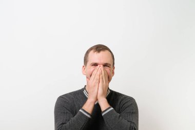 Adam gülüyor ve ağzını kapatıyor.