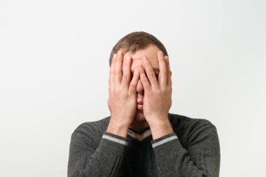  Adam elleriyle yüzünü kapatıyor.