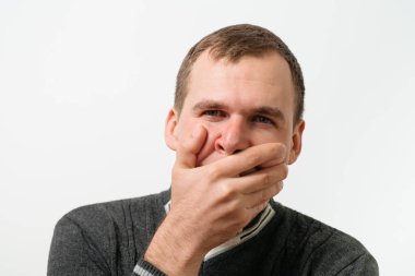 Adam gülüyor ve ağzını kapatıyor.