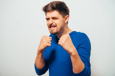 Boksör pozisyonunda duran ve yumruklarını sıkmaya hazır genç bir adamın yakın plan portresi.