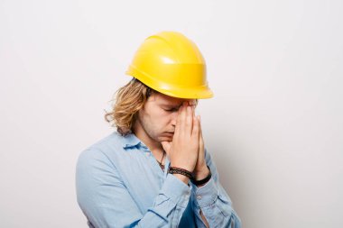Construction worker praying against studio background  clipart
