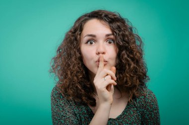 Kadın parmağını dudaklarına koydu.