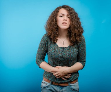 Stüdyo arka planında karın ağrısı olan kadın.