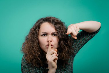 Kadın parmağını dudaklarına koydu.