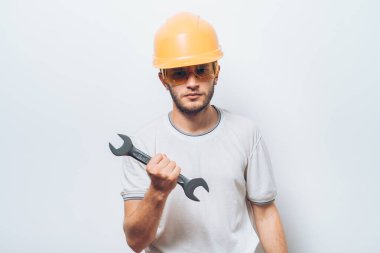 İngiliz anahtarı tutan genç işçinin portresi.