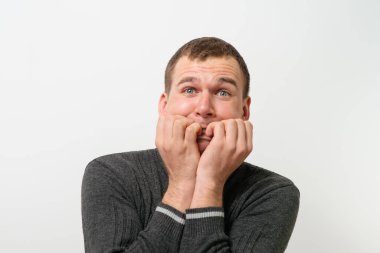 Adam tırnaklarını stüdyonun arka planında yiyor.