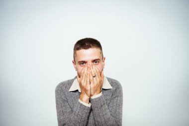 Adam gülüyor ve ağzını kapatıyor.