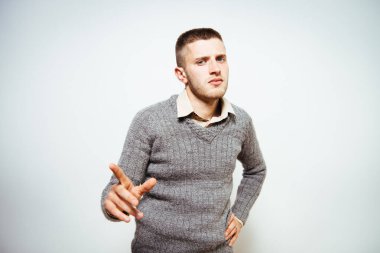 Genç adam işaret parmağını kameraya doğru gösteriyor.