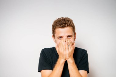 Adam gülüyor ve ağzını kapatıyor.