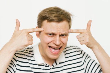 Parmağıyla şakağına dokunan öfkeli bir adamın yakın plan portresi. Delirdin mi sen??