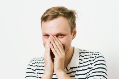 Adam gülüyor ve ağzını kapatıyor.