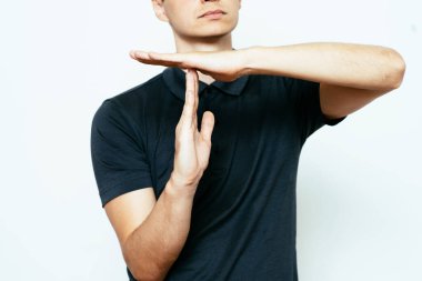 Bir adam, ellerin mola verdiğini gösterir. Gri bir arkaplanda.