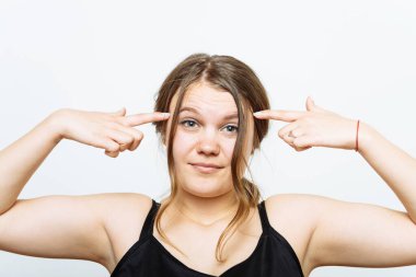 Parmağını şakağına dayayıp düşünen bir kadın. Gri bir arkaplanda.