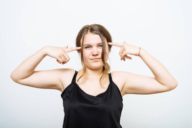 Parmağını şakağına dayayıp düşünen bir kadın. Gri bir arkaplanda.