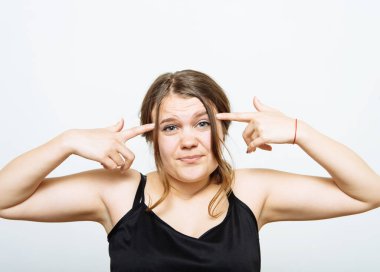 Parmağını şakağına dayayıp düşünen bir kadın. Gri bir arkaplanda.