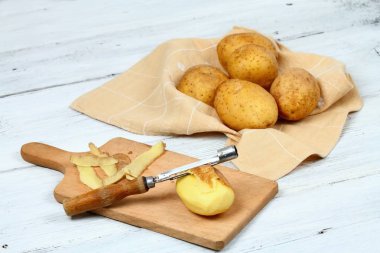 Beyaz masa üzerinde eski soyma ile ham patates soyarken oldu