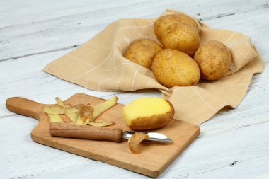 Beyaz masa üzerinde eski soyma ile ham patates soyarken oldu