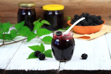 Taze ev yapımı böğürtlen reçeli Beyaz ahşap masa üzerinde bir kavanoz içinde.