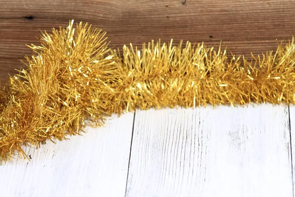 Χριστουγεννιάτικη χρυσή αλυσίδα σε λευκό ξύλινο τραπέζι με καφέ φόντο — Φωτογραφία Αρχείου