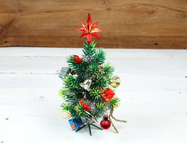 Beautiful Christmas tree with a star on white wooden table. — Stock Photo, Image