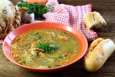 Bol sebzeli mercimek çorbası, üstünde maydanoz ve baget. Kırmızı tabakta mercimek, havuç, kereviz ve pırasa çorbası.. 