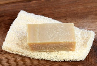 Havluda bir kalıp sabun, kırsal tarzda. Ahşap masada el yapımı zeytinyağı sabunu..