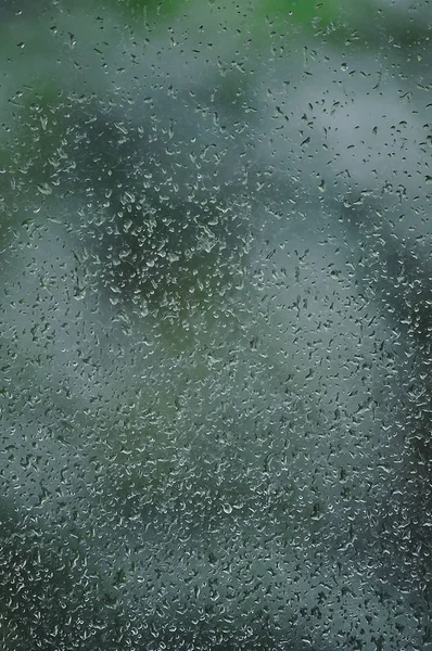Regenachtige dag, regendruppels op natte vensterglas, verticale heldere abstract regen water achtergrond patroon detail, macro close-up, gedetailleerde groene, blauwe, donkere levendige grijze waterdrops, zachte bokeh, pluvial regen seizoen concept — Stockfoto