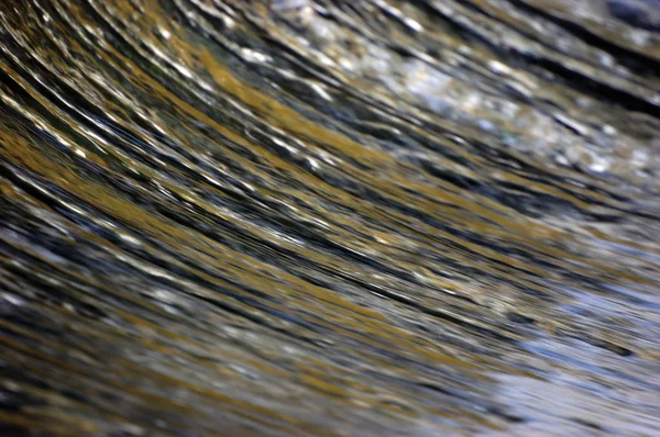Cascada de agua cascada que fluye torrente salpica el fondo, gran primer plano horizontal detallado, azul brillante, dorado, amarillo, colores pastel verde mar, movimiento borroso gotas patrón de textura, bokeh textura suave — Foto de Stock