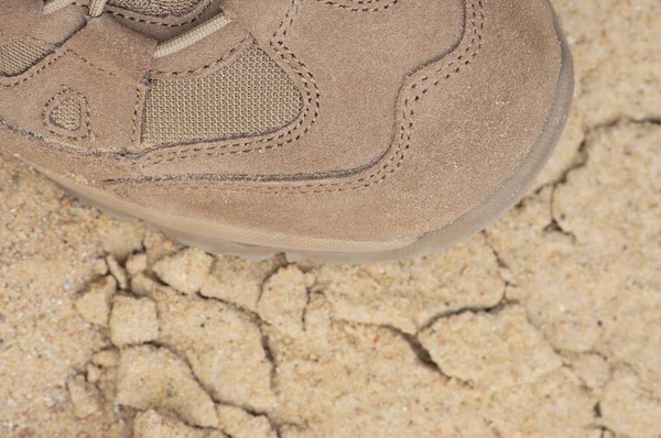 Brand new suede and nylon beige tan camo military tactical desert combat boot, arid dried soil and sand, detailed horizontal background macro close-up, bare earth, dust, pebbles, rough terrain off-road trekking, hiking concept — Stock Photo, Image