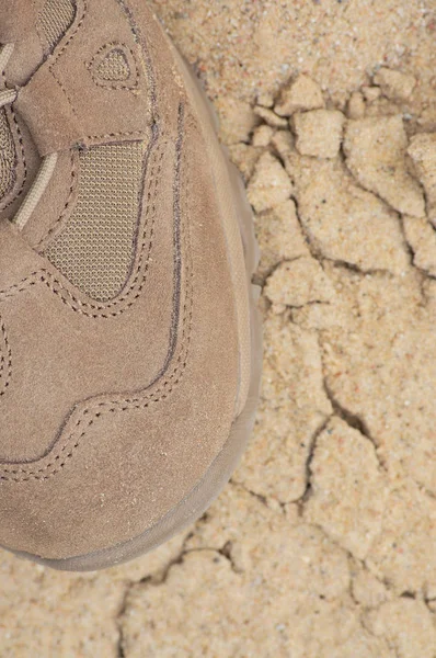 Brand new suede and nylon beige tan camo military tactical desert combat boot, arid dried soil and sand, detailed vertical background macro close-up, bare earth, dust, pebbles, rough terrain off-road trekking, hiking concept — Stock Photo, Image