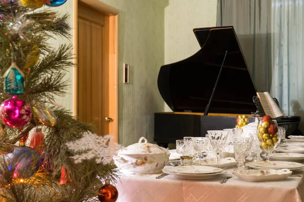 Інтер'єр вітальні з красивою прикрашеною ялинкою, святковим столом та старовинним піаніно. Концепція новорічного відпочинку в затишному будинку — стокове фото