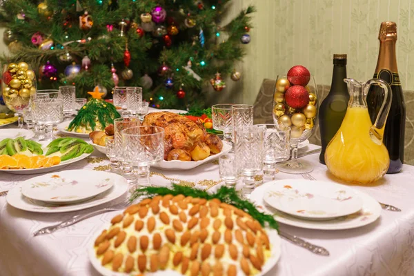 Mesa servida com pratos festivos perto de bela árvore de Natal decorada no interior da sala de estar. Conceito de feriado de ano novo em casa acolhedora — Fotografia de Stock