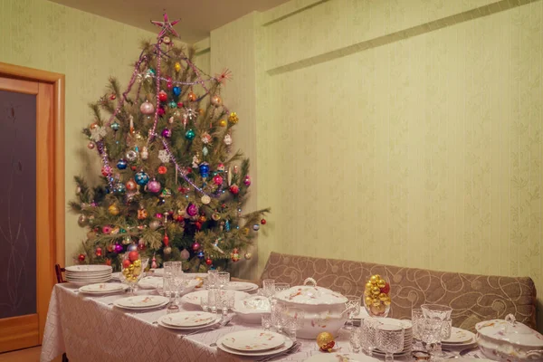 Geserveerd tafel met feestelijke vaatwerk in de buurt van mooi versierde kerstboom in woonkamer interieur. Concept van het nieuwe jaar vakantie gezellig thuis. Selectieve aandacht, vintage Toon — Stockfoto