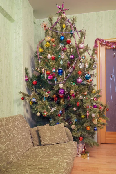 Beautiful big decorated Christmas tree with many multi colored toys in living room interior. Concept of new year holiday at cozy home. Vintage tone — Stockfoto