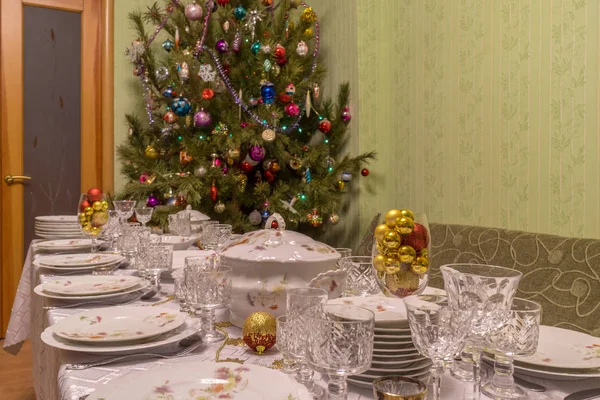 Mesa servida com utensílios de mesa festivos perto de bela árvore de Natal decorada no interior da sala de estar. Conceito de feriado de ano novo em casa acolhedora — Fotografia de Stock