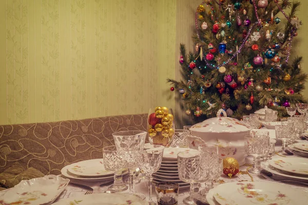 Szolgált táblázat közelében gyönyörű díszített karácsonyfa nappali belső ünnepi étkészlet. Újévi ünnep fogalmának barátságos otthon. Vintage hang — Stock Fotó