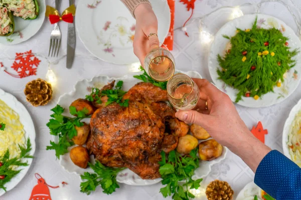 Köpüklü şarapla bardakları tutan insan elleri. Arkadaşlar ya da aile şenlikli Noel masasında şampanyayla kadeh kaldırıyor. Xmas yemeği, lezzetli yemekler, sıcacık evde kış tatili kutlaması. — Stok fotoğraf