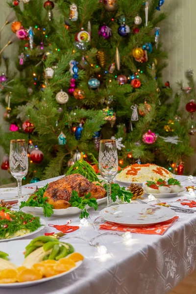 Navidad festiva sirvió mesa contra hermoso pino verde decorado con muchos juguetes coloridos de año nuevo. Cena de Navidad, comida deliciosa, pavo de Navidad. Celebración de las vacaciones de invierno en casa acogedora — Foto de Stock